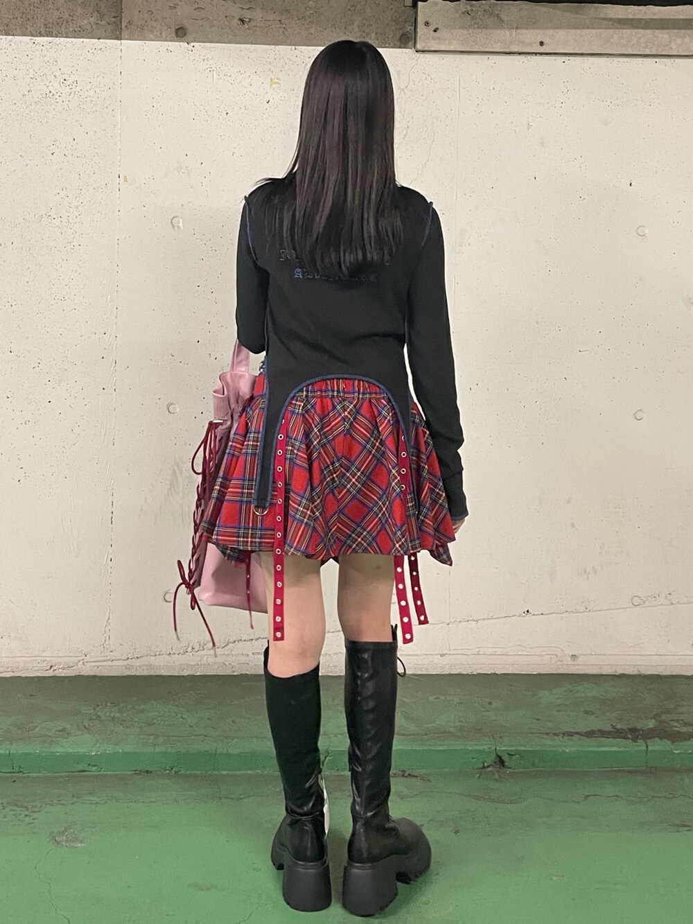 レッド系のスカート、ブラック系のブーツ、ブラック系のTシャツ/カットソーを着用したレディースの秋コーディネートの5枚目の写真