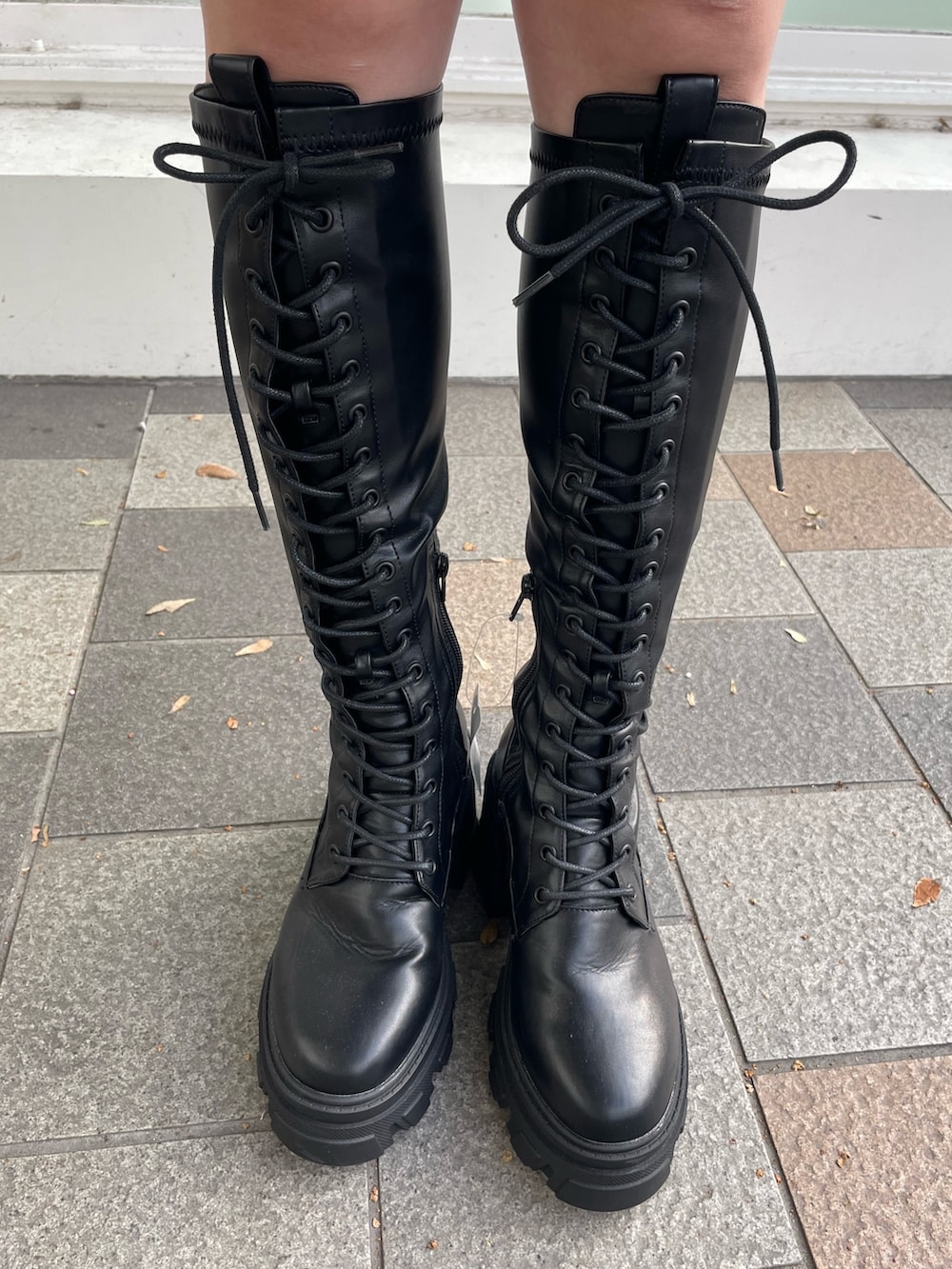 ブラック系のシャツワンピース、レッド系のダウンベスト、ブラック系のブーツを着用したレディースの秋コーディネートの10枚目の写真