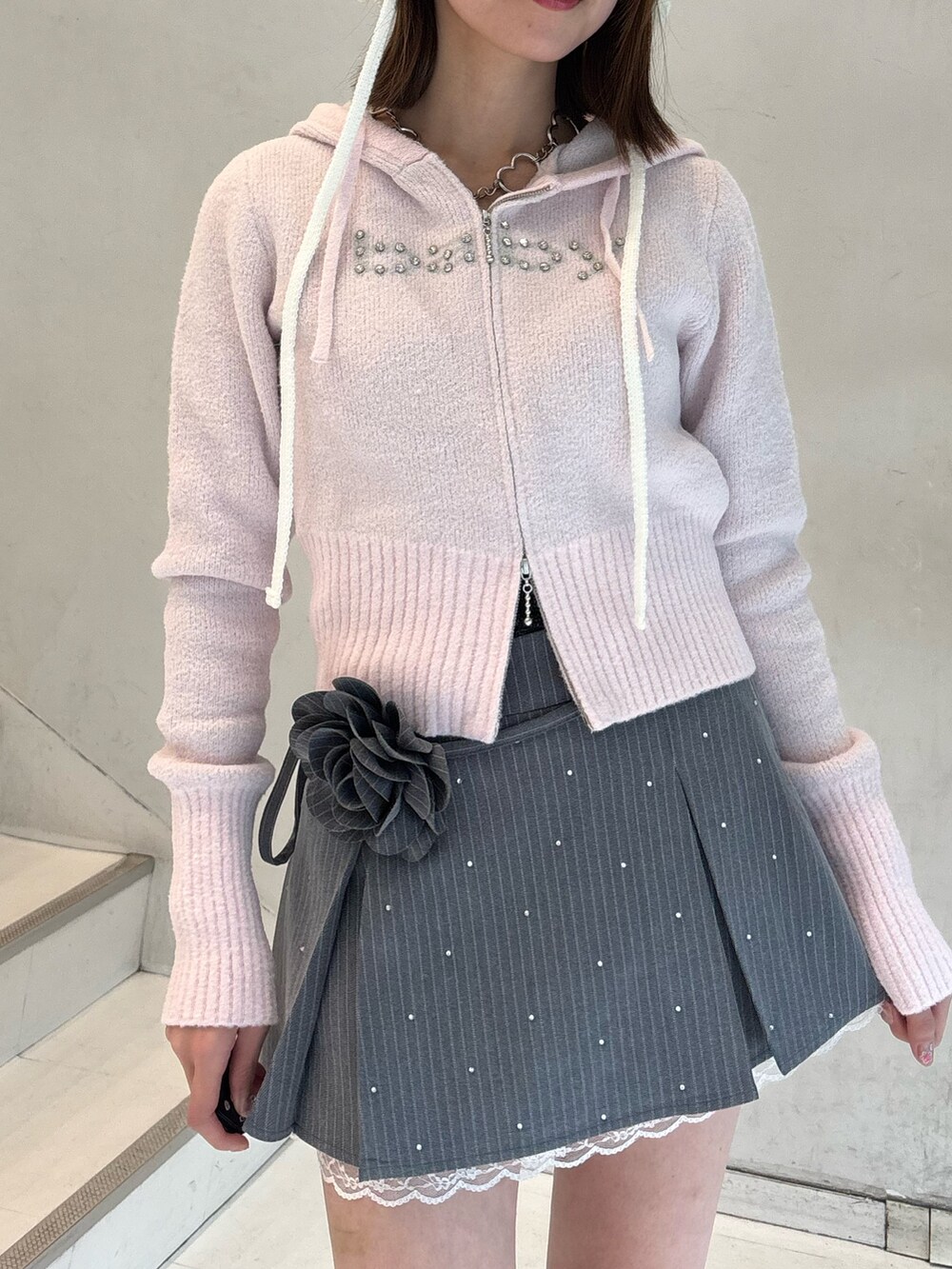 ピンク系のパーカー、グレー系のスカート、ホワイト系のブーツを着用したレディースの冬コーディネートの7枚目の写真