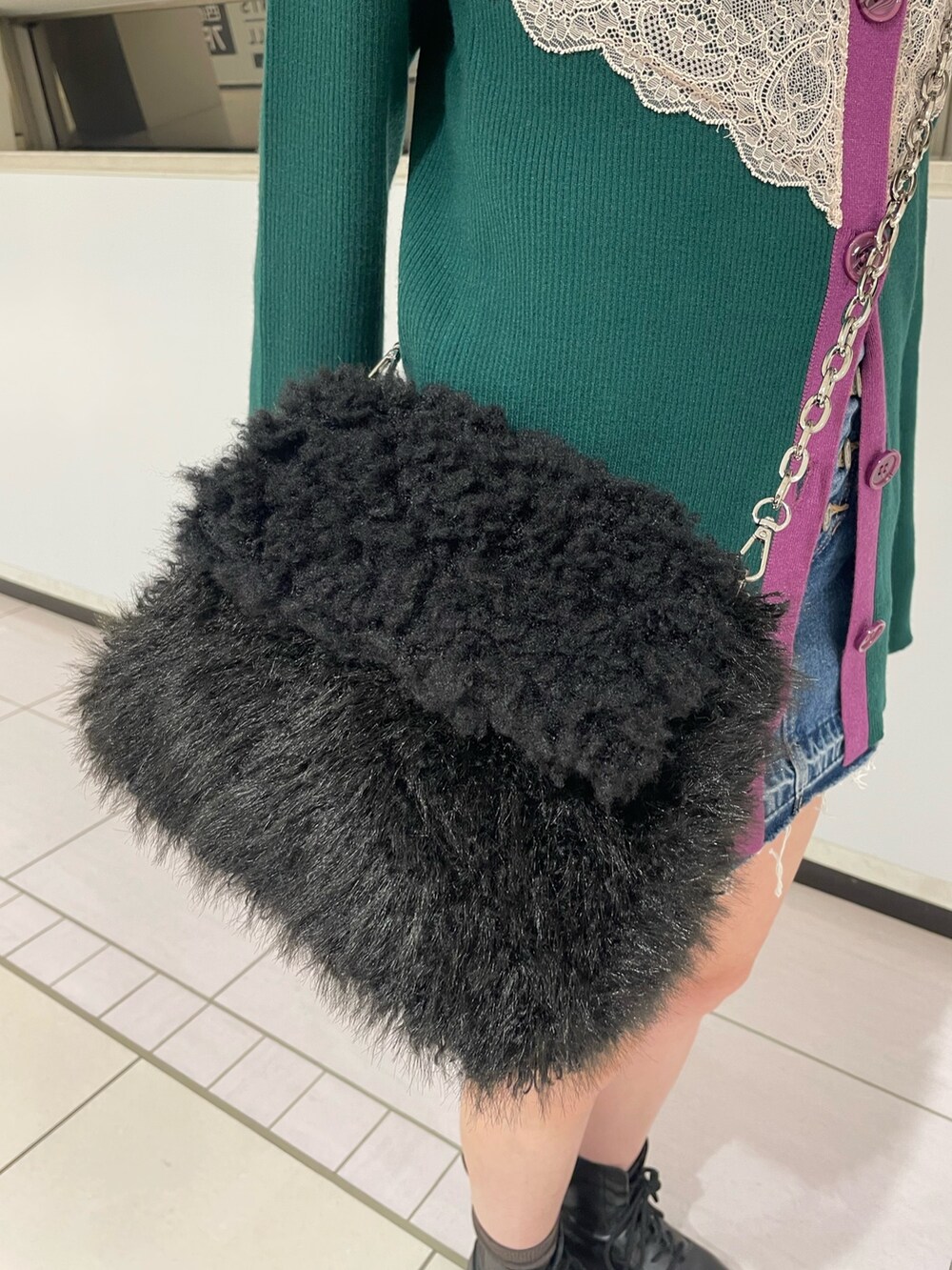 グリーン系のカーディガン/ボレロ、ブルー系のデニムパンツ、ブラック系のハンドバッグを着用したレディースの冬コーディネートの9枚目の写真