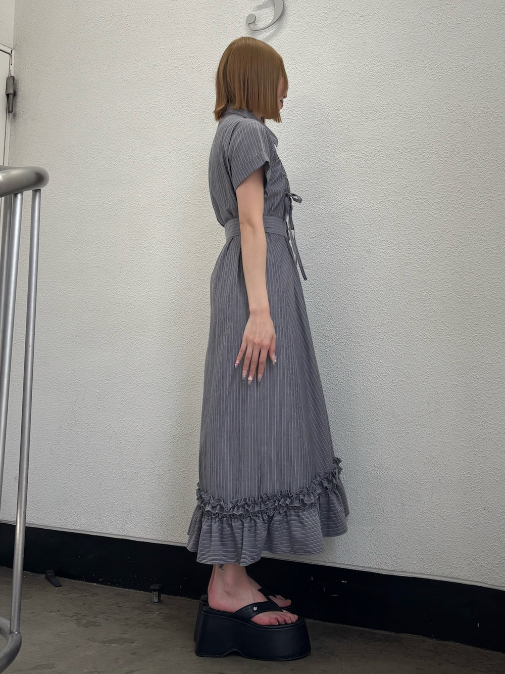 グレー系のワンピース、ブラック系のサンダル、シルバー系のネックレスを着用したレディースの春コーディネートの3枚目の写真