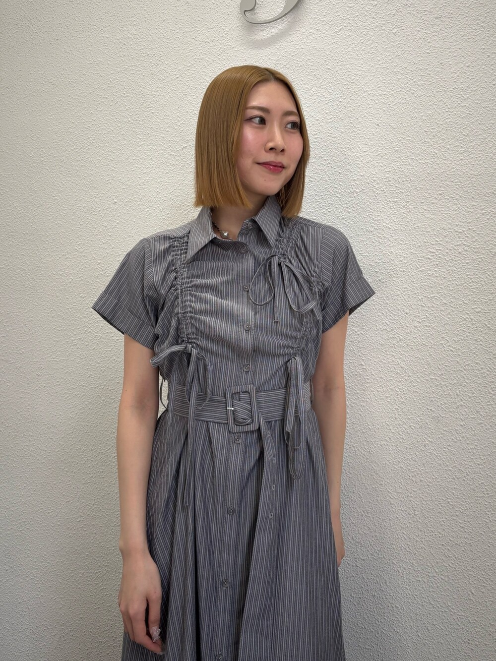 グレー系のワンピース、ブラック系のサンダル、シルバー系のネックレスを着用したレディースの春コーディネートの5枚目の写真
