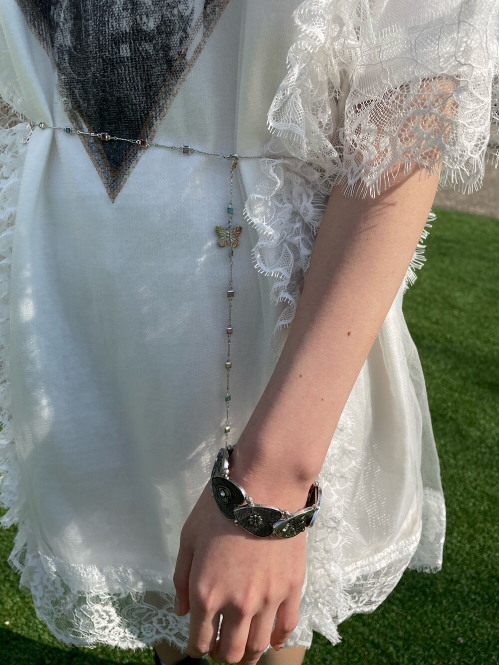 ホワイト系のワンピース、シルバー系のベルト、シルバー系のネックレスを着用したレディースの春コーディネートの9枚目の写真