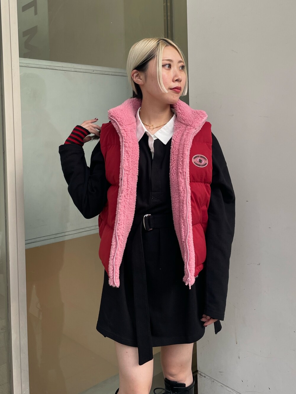 ブラック系のシャツワンピース、レッド系のダウンベスト、ブラック系のブーツを着用したレディースの秋コーディネートの6枚目の写真