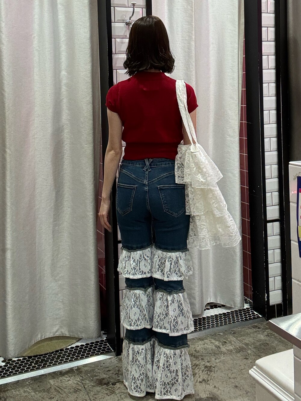 ブルー系のデニムパンツ、ホワイト系のトートバッグ、レッド系のニット/セーターを着用したレディースの春コーディネートの4枚目の写真