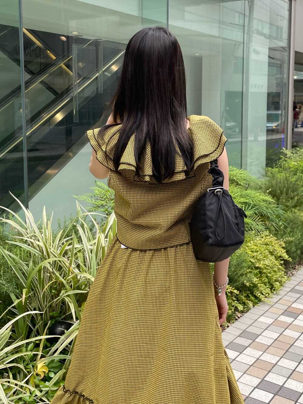 イエロー系のスカート、イエロー系のシャツ/ブラウス、ブラック系のショルダーバッグを着用したレディースの夏コーディネートの5枚目の写真