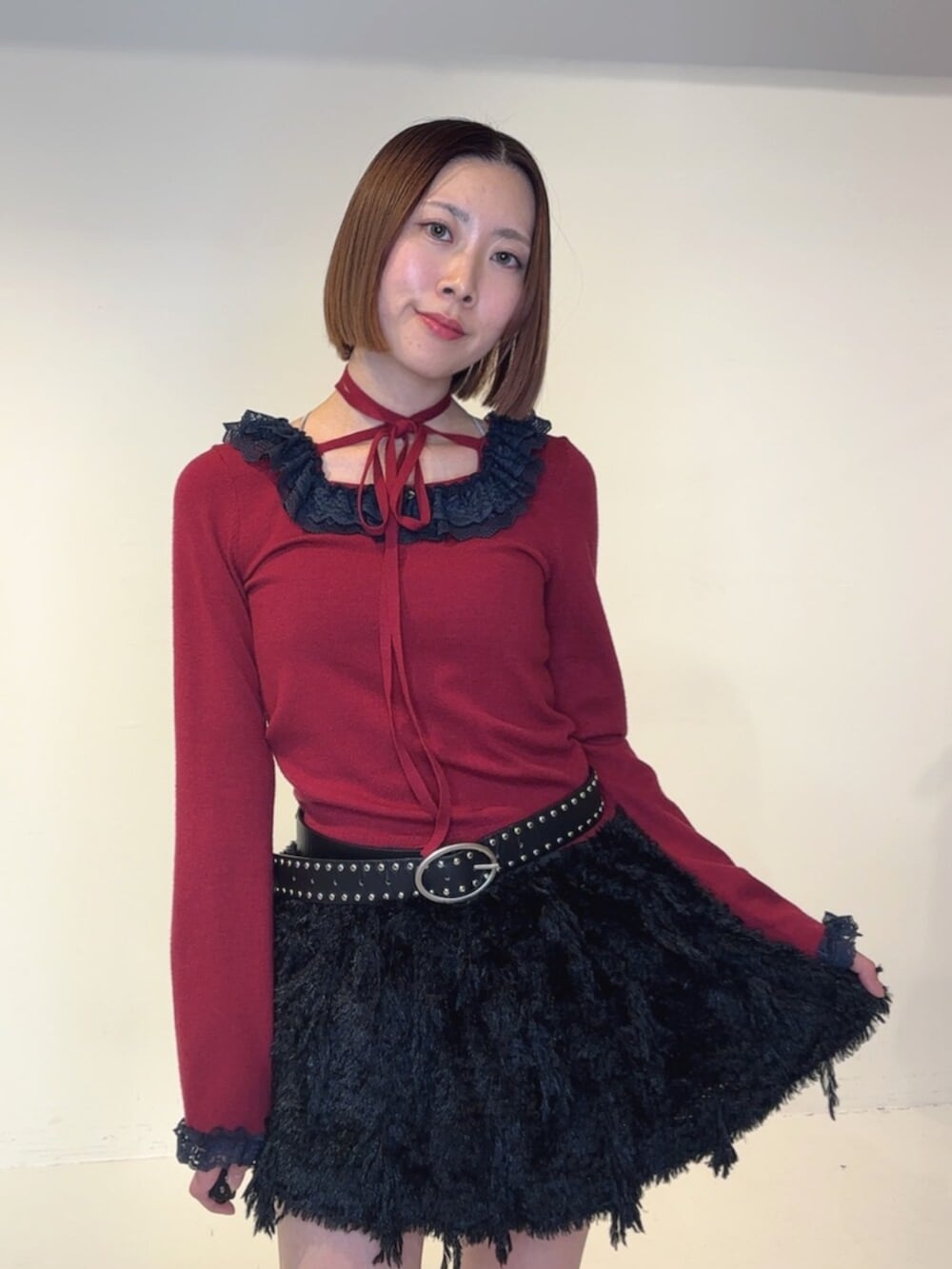 ブラック系のブーツ、ブラック系のスカート、レッド系のニット/セーターを着用したレディースの秋コーディネートの5枚目の写真