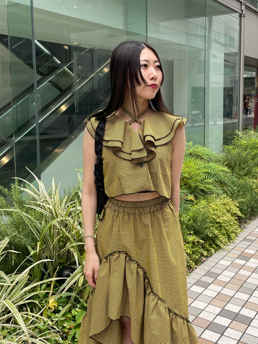 イエロー系のスカート、イエロー系のシャツ/ブラウス、ブラック系のショルダーバッグを着用したレディースの夏コーディネートの3枚目の写真
