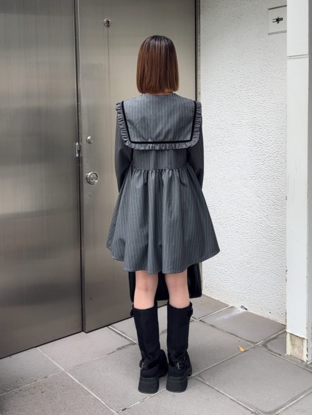 ブラック系のブーツ、ブラック系のハンドバッグ、グレー系のワンピースを着用したレディースの秋コーディネートの4枚目の写真