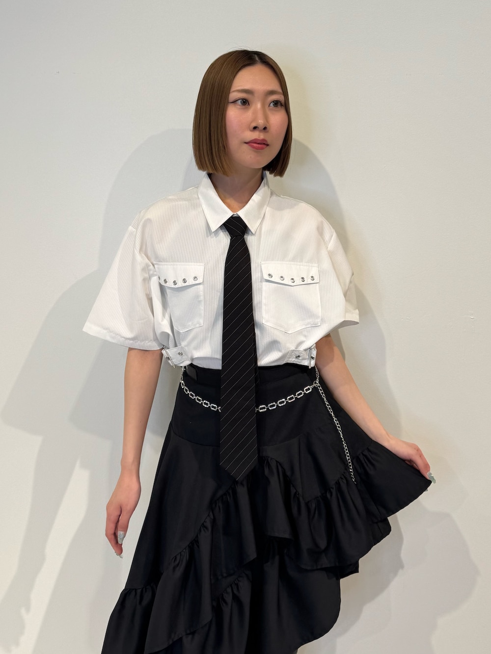 ホワイト系のシャツ/ブラウス、ブラック系のスカート、ブラック系のネクタイを着用したレディースの春コーディネートの5枚目の写真