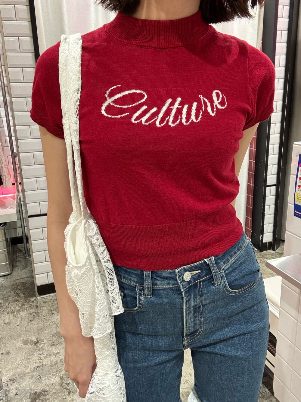 ブルー系のデニムパンツ、ホワイト系のトートバッグ、レッド系のニット/セーターを着用したレディースの春コーディネートの8枚目の写真