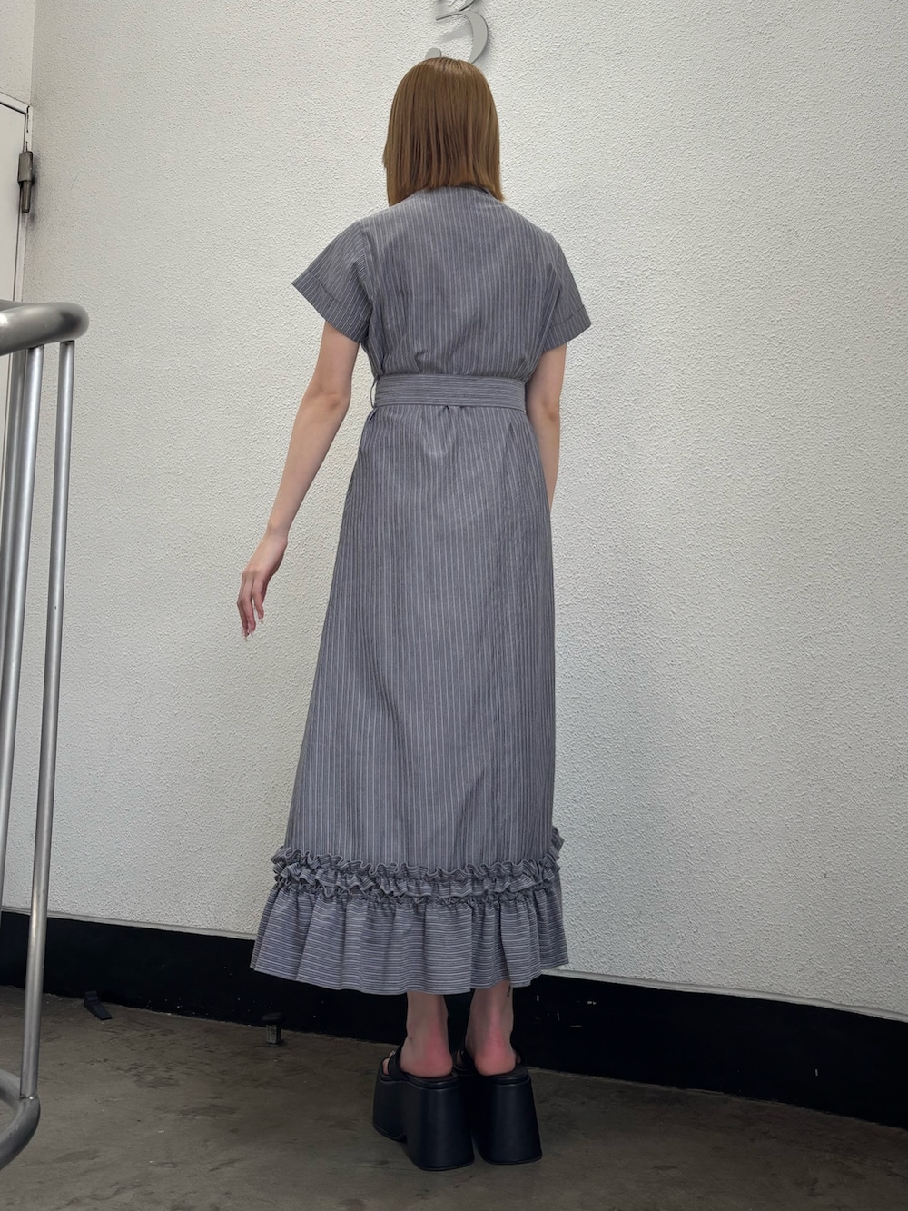 グレー系のワンピース、ブラック系のサンダル、シルバー系のネックレスを着用したレディースの春コーディネートの4枚目の写真
