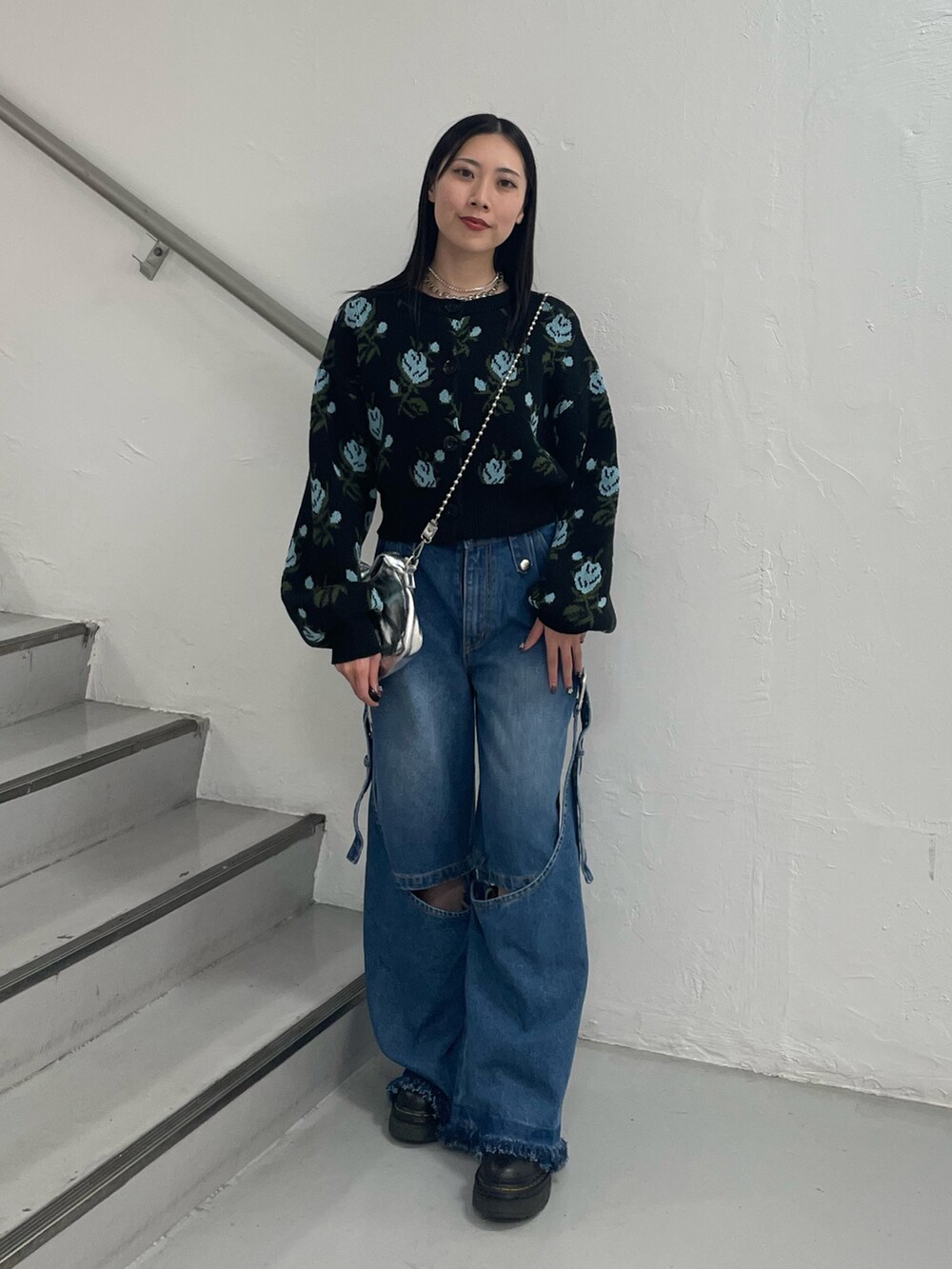 ブルー系のデニムパンツ、ブラック系のカーディガン/ボレロ、シルバー系のハンドバッグを着用したレディースの秋コーディネートの3枚目の写真