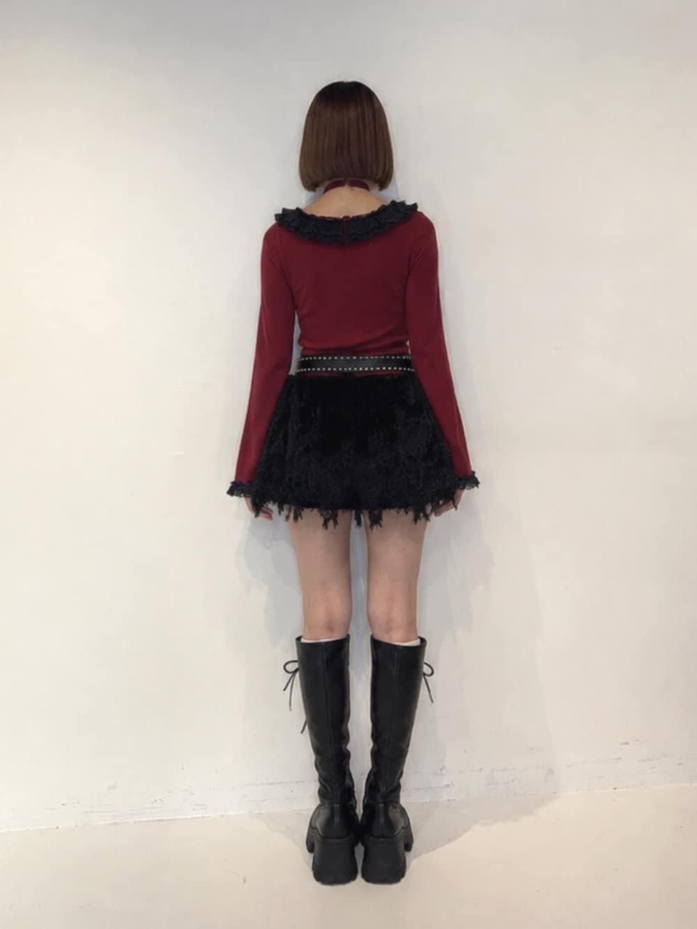 ブラック系のブーツ、ブラック系のスカート、レッド系のニット/セーターを着用したレディースの秋コーディネートの4枚目の写真