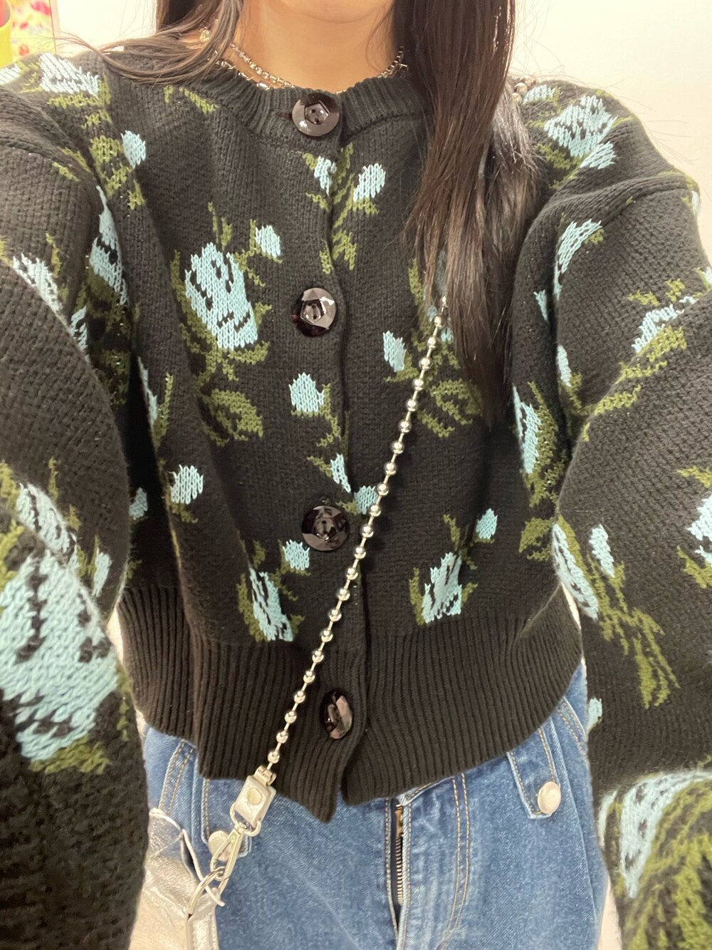 ブルー系のデニムパンツ、ブラック系のカーディガン/ボレロ、シルバー系のハンドバッグを着用したレディースの秋コーディネートの8枚目の写真