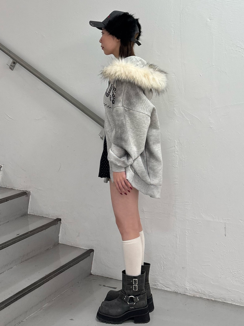 ブラック系のスカート、グレー系のパーカー、ブラック系のブーツを着用したレディースの冬コーディネートの3枚目の写真