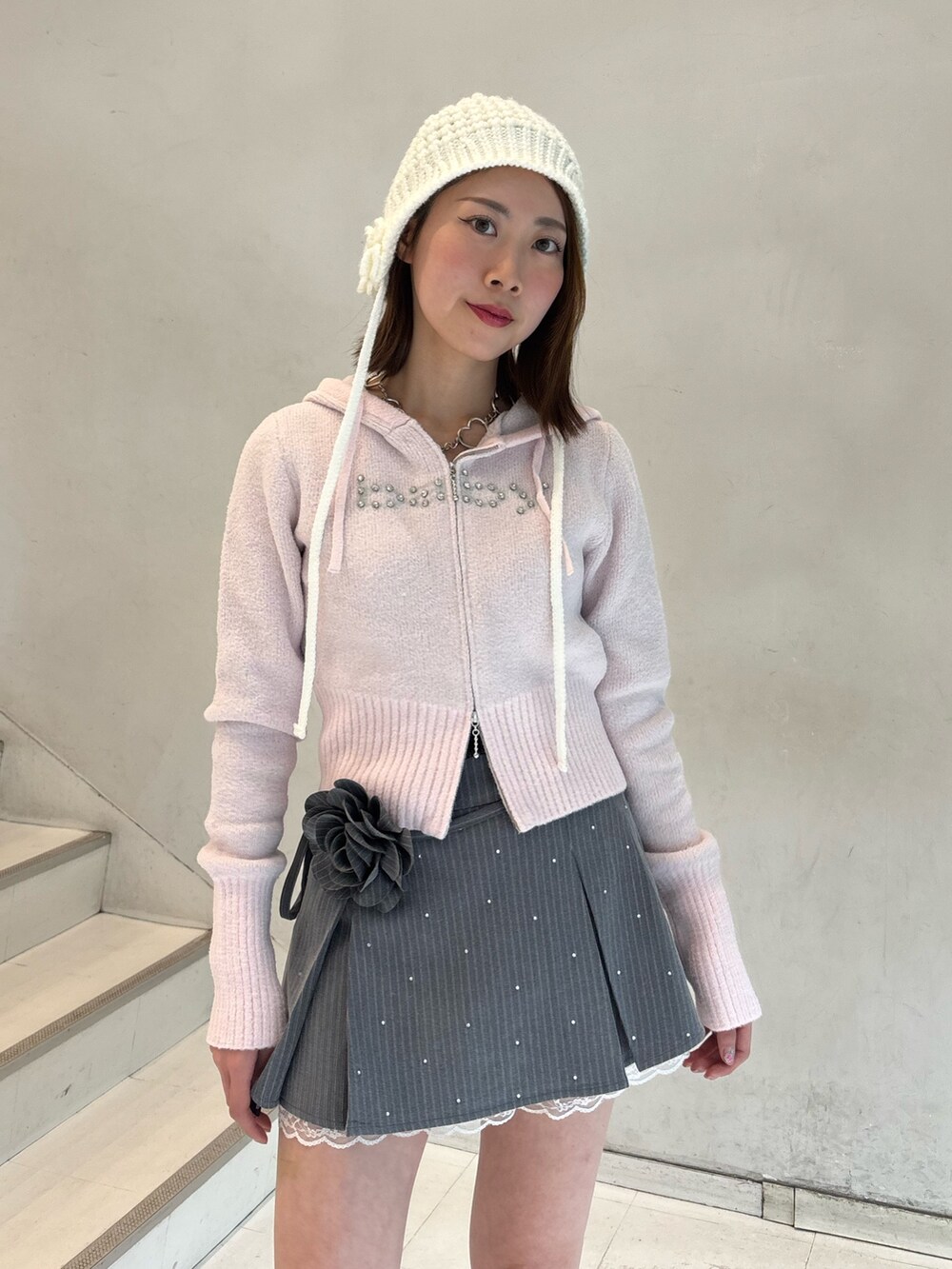 ピンク系のパーカー、グレー系のスカート、ホワイト系のブーツを着用したレディースの冬コーディネートの5枚目の写真