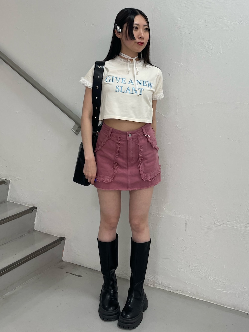 ピンク系のスカート、ホワイト系のTシャツ/カットソー、ブラック系のショルダーバッグを着用したレディースの春コーディネートの2枚目の写真