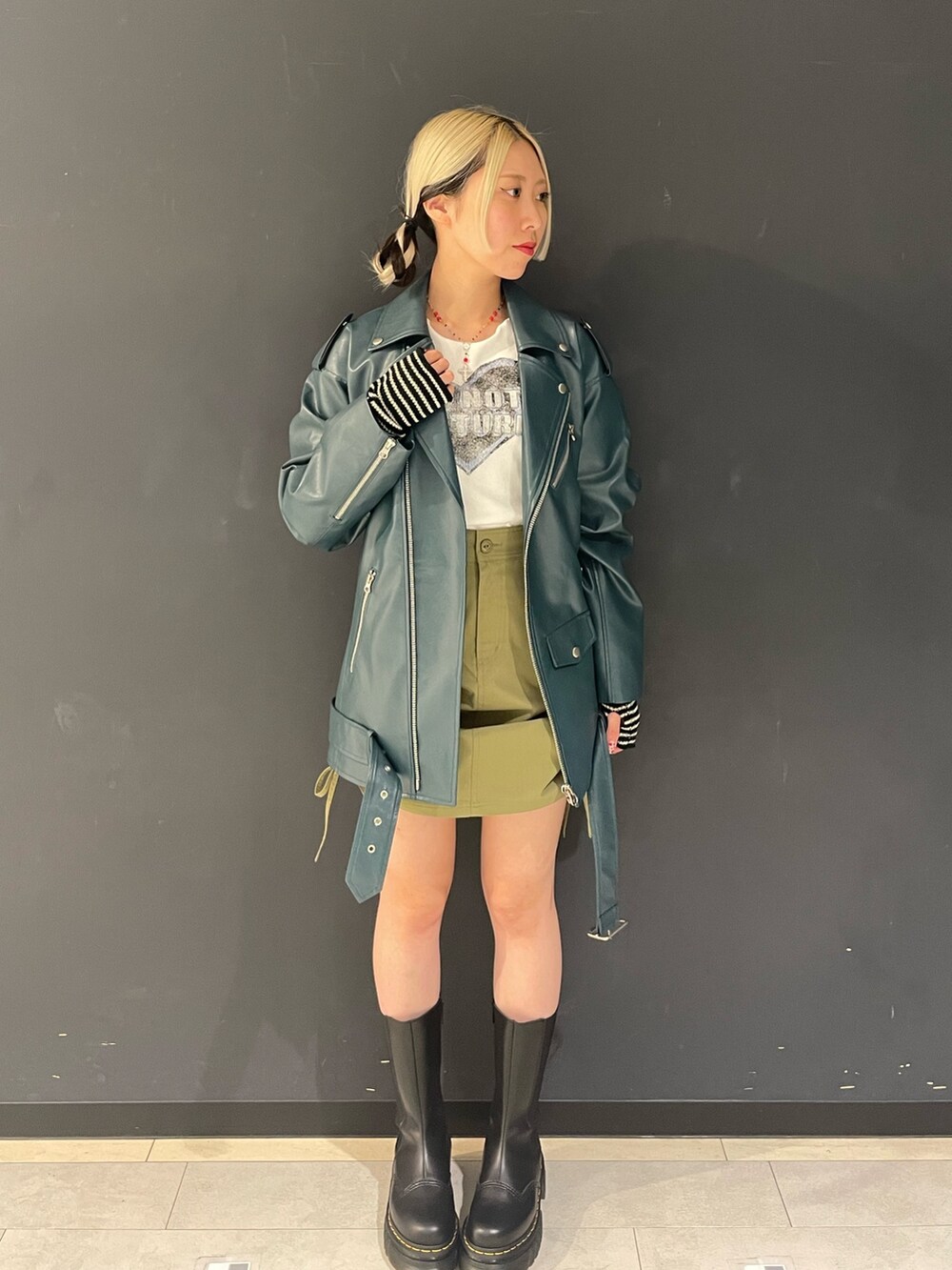 ホワイト系のTシャツ/カットソー、グリーン系のスカート、ブルー系のライダースジャケットを着用したレディースの秋コーディネートの2枚目の写真