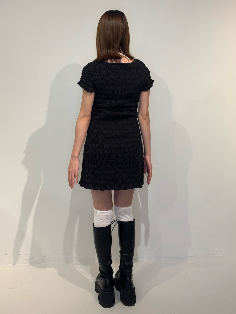 ブラック系のワンピース、ブラック系のブーツ、ホワイト系のキャミソールを着用したレディースの冬コーディネートの4枚目の写真