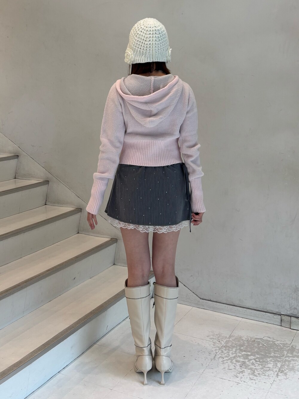 ピンク系のパーカー、グレー系のスカート、ホワイト系のブーツを着用したレディースの冬コーディネートの4枚目の写真