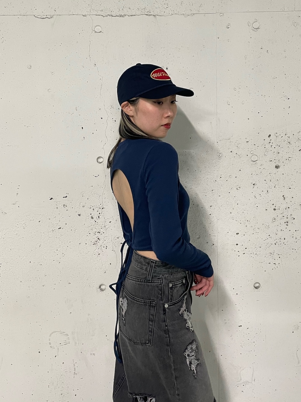 ブラック系のデニムスカート、ブラック系のTシャツ/カットソー、ブルー系のキャップを着用したレディースの冬コーディネートの5枚目の写真