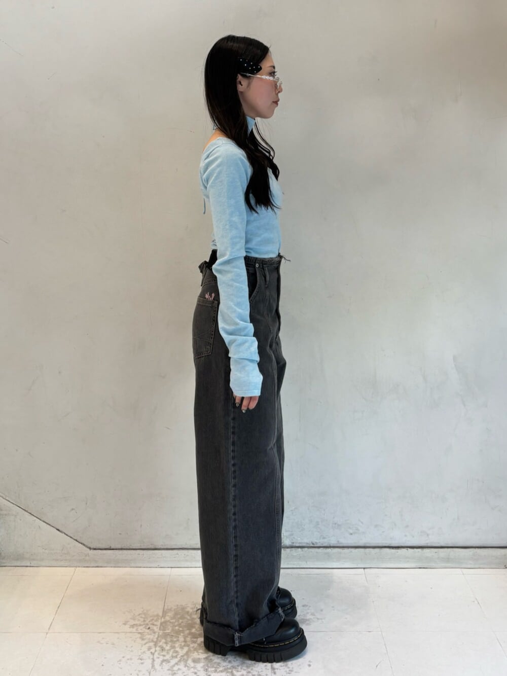 ブラック系のデニムパンツ、ブルー系のニット/セーター、シルバー系のメガネを着用したレディースの冬コーディネートの3枚目の写真