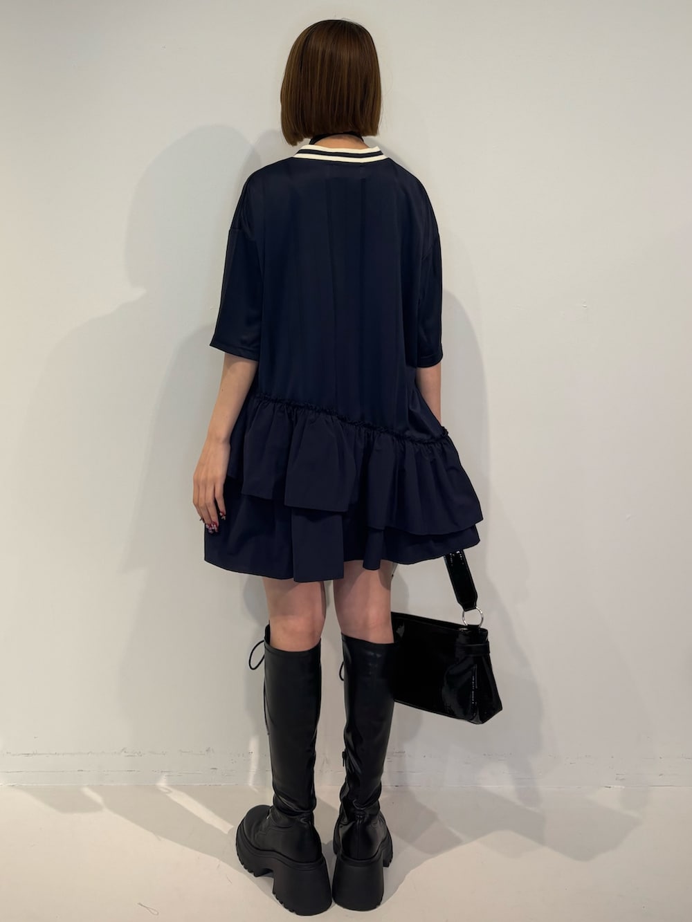 ブルー系のワンピース、ブラック系のハンドバッグ、ブラック系のブーツを着用したレディースの冬コーディネートの4枚目の写真