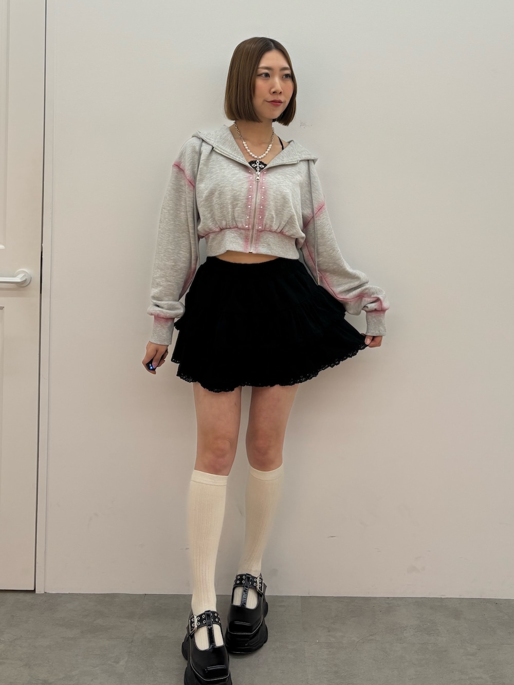 グレー系のパーカー、ブラック系のローファー、シルバー系のネックレスを着用したレディースの春コーディネートの2枚目の写真