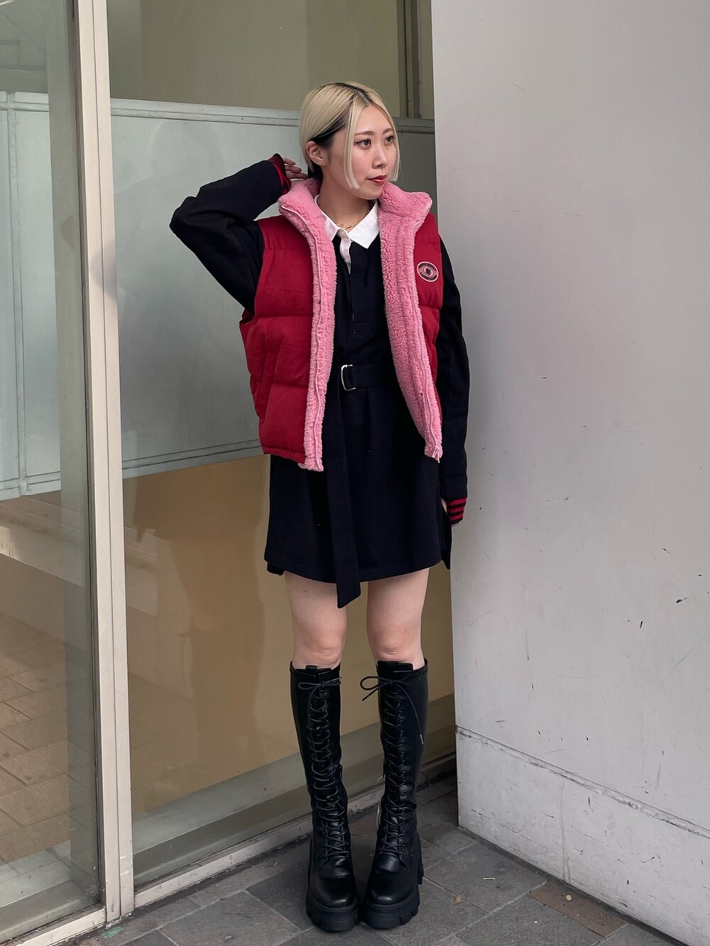 ブラック系のシャツワンピース、レッド系のダウンベスト、ブラック系のブーツを着用したレディースの秋コーディネートの2枚目の写真