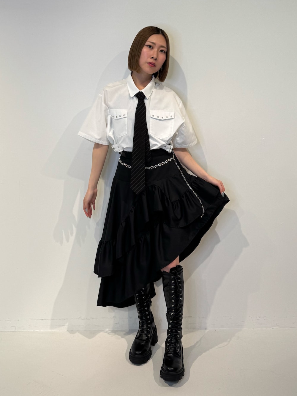 ホワイト系のシャツ/ブラウス、ブラック系のスカート、ブラック系のネクタイを着用したレディースの春コーディネートの2枚目の写真