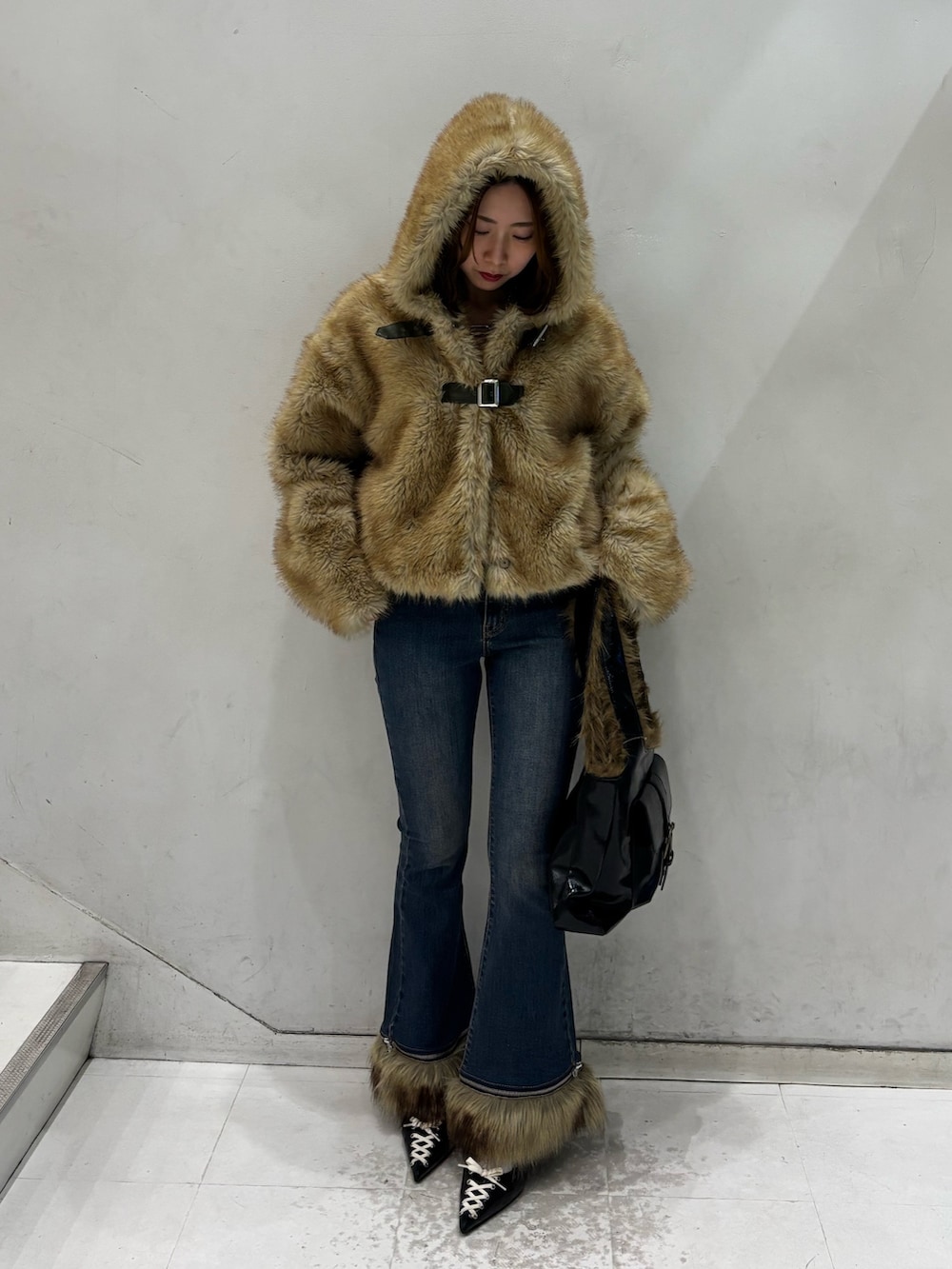 ブルー系のデニムパンツ、ブラック系のハンドバッグ、ブラック系のパンプスを着用したレディースの秋コーディネートの5枚目の写真