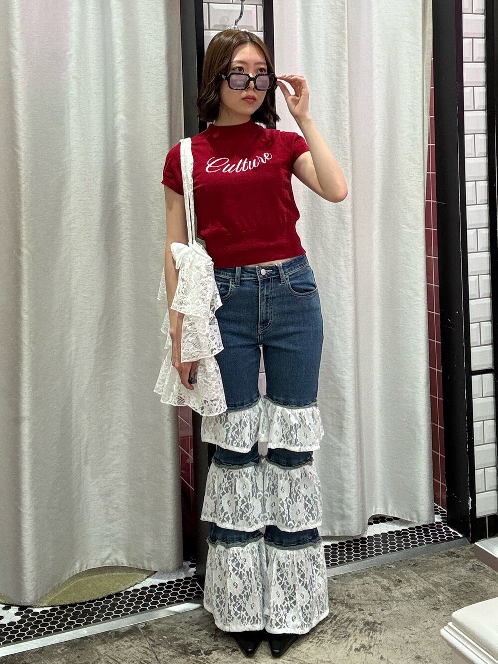 ブルー系のデニムパンツ、ホワイト系のトートバッグ、レッド系のニット/セーターを着用したレディースの春コーディネートの2枚目の写真