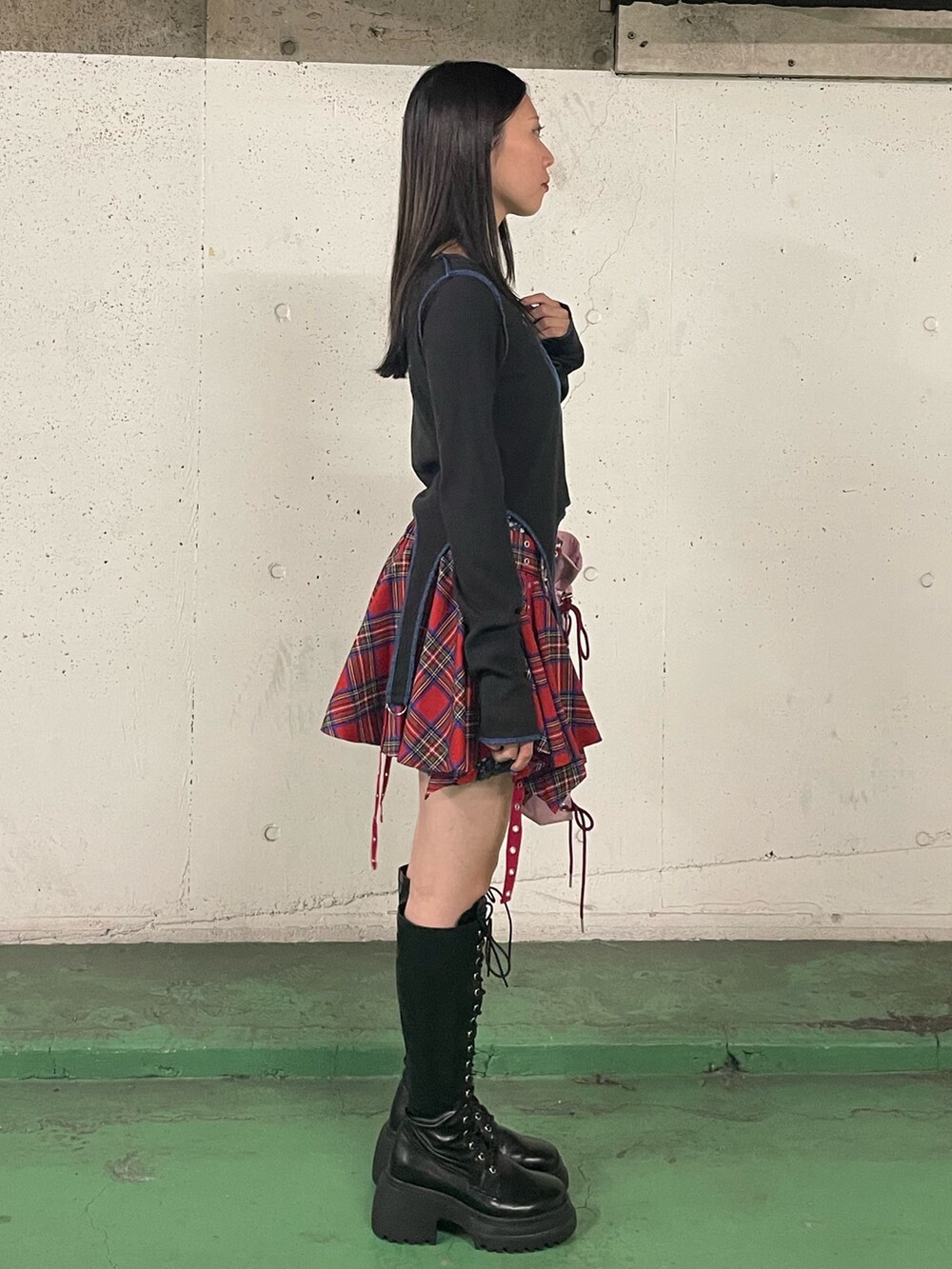 レッド系のスカート、ブラック系のブーツ、ブラック系のTシャツ/カットソーを着用したレディースの秋コーディネートの4枚目の写真