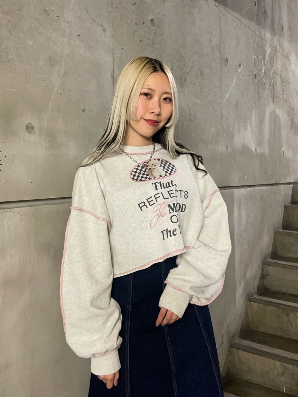 グレー系のスウェット、ブルー系のジャンパースカート、ブラック系のブーツを着用したレディースの冬コーディネートの5枚目の写真