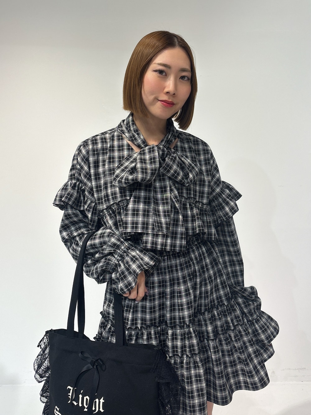 ブラック系のワンピース、ブラック系のトートバッグ、ブラック系のブーツを着用したレディースの冬コーディネートの6枚目の写真