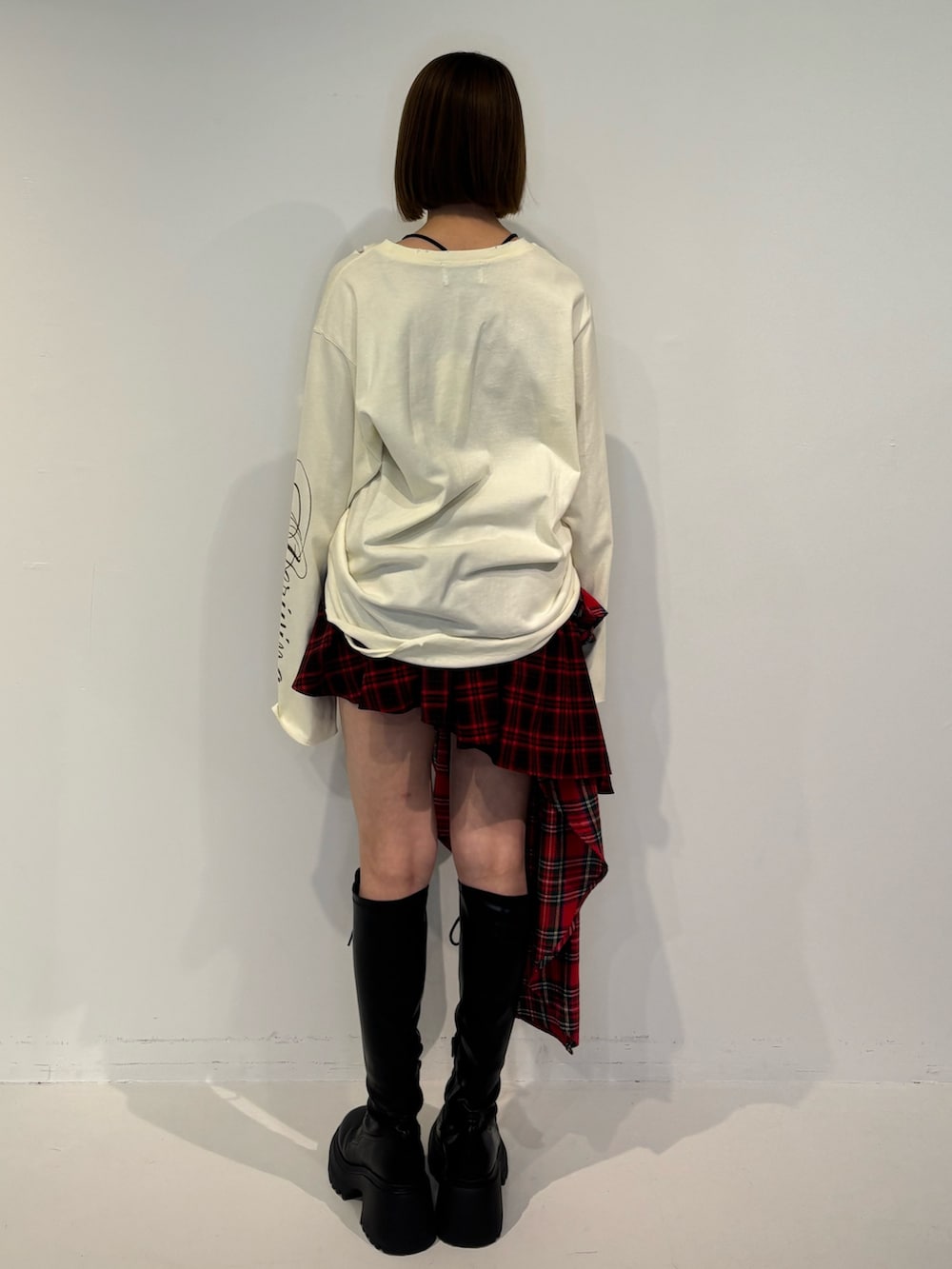 ブラック系のブーツ、ホワイト系のTシャツ/カットソー、レッド系のスカートを着用したレディースの冬コーディネートの4枚目の写真