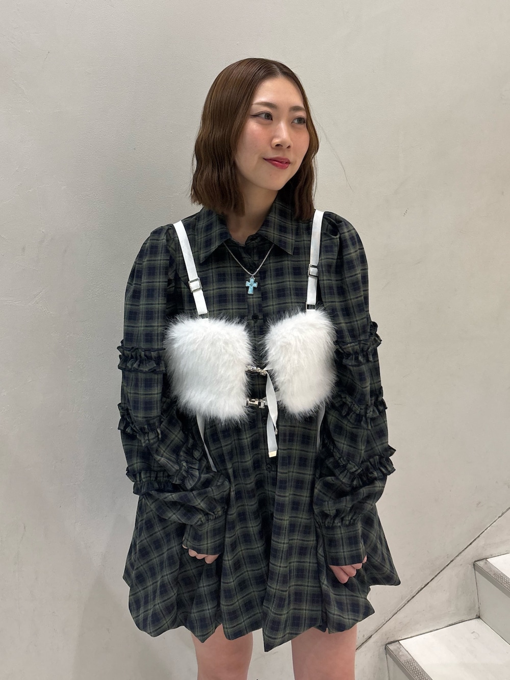 グリーン系のワンピース、ブラック系のブーツ、ホワイト系のベルトを着用したレディースの冬コーディネートの6枚目の写真