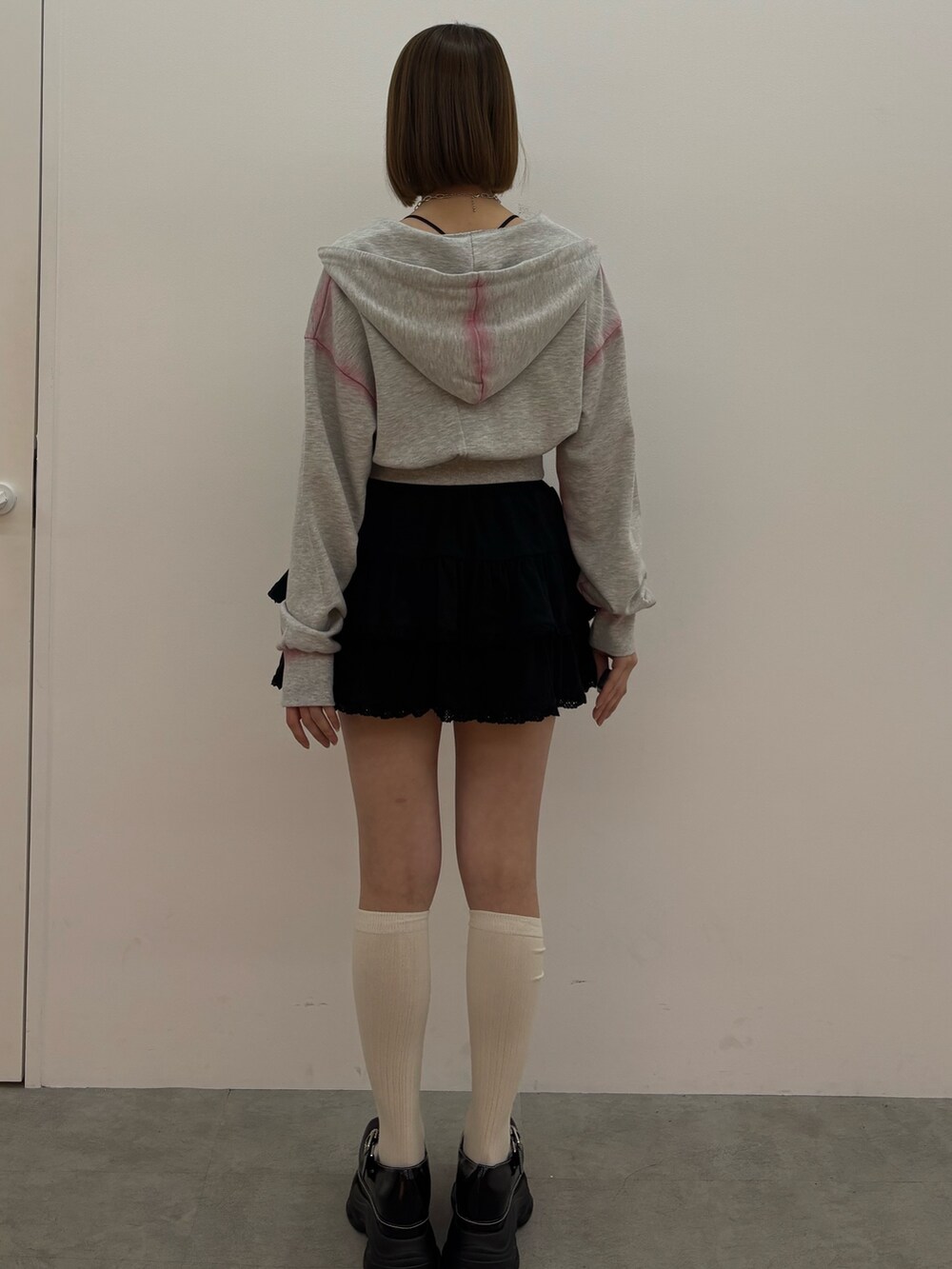 グレー系のパーカー、ブラック系のローファー、シルバー系のネックレスを着用したレディースの春コーディネートの4枚目の写真