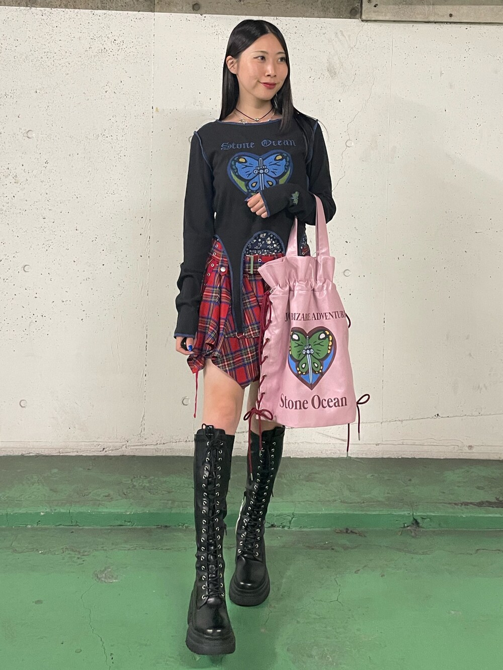 レッド系のスカート、ブラック系のブーツ、ブラック系のTシャツ/カットソーを着用したレディースの秋コーディネートの2枚目の写真