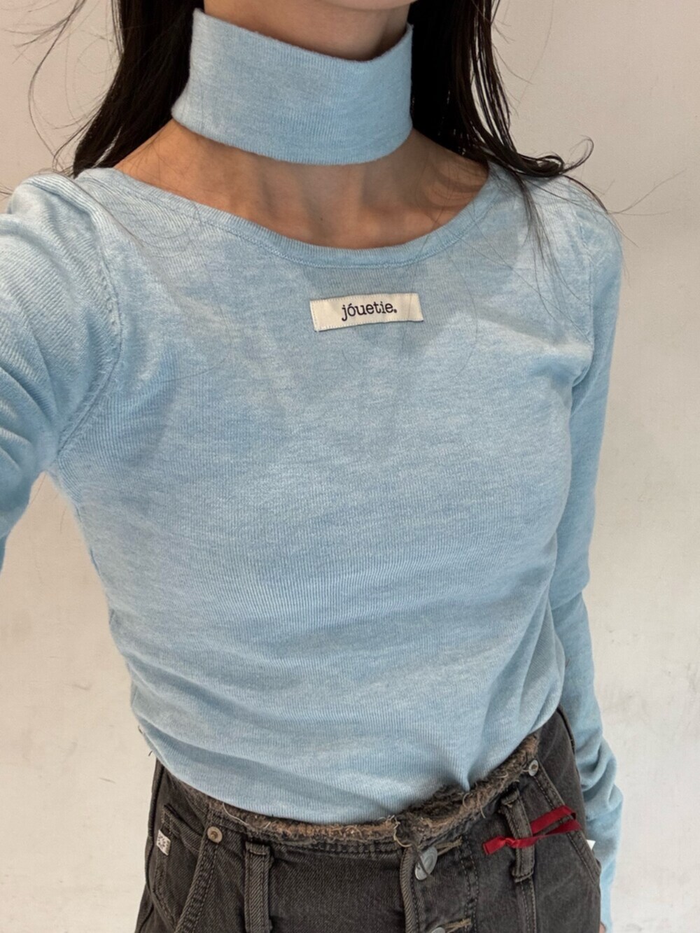 ブラック系のデニムパンツ、ブルー系のニット/セーター、シルバー系のメガネを着用したレディースの冬コーディネートの8枚目の写真