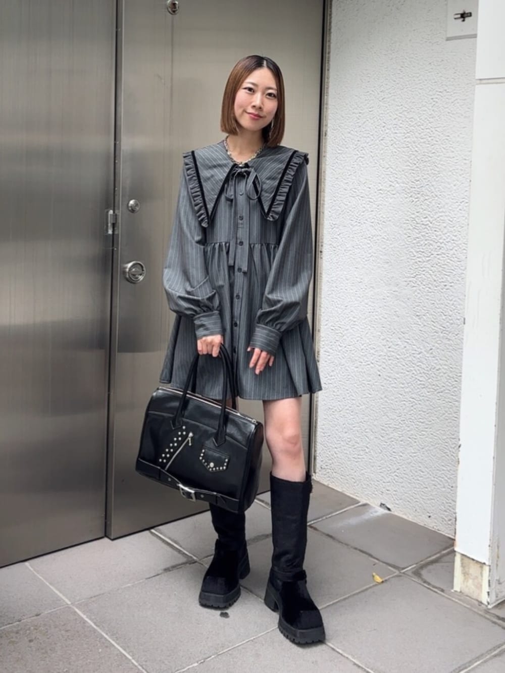 ブラック系のブーツ、ブラック系のハンドバッグ、グレー系のワンピースを着用したレディースの秋コーディネートの2枚目の写真