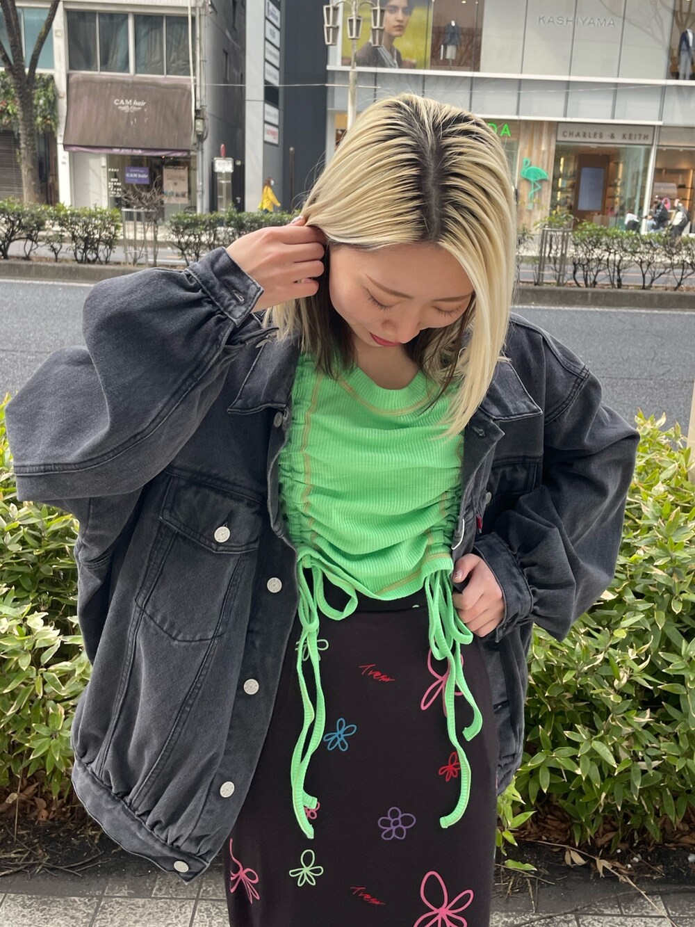 ブラック系のスカート、グリーン系のTシャツ/カットソー、ブラック系のデニムジャケットを着用したレディースの春コーディネートの6枚目の写真