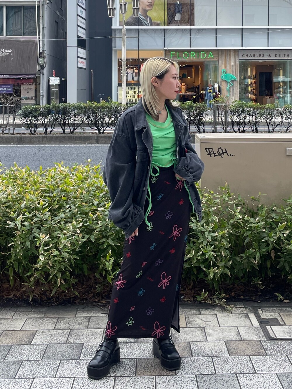 ブラック系のスカート、グリーン系のTシャツ/カットソー、ブラック系のデニムジャケットを着用したレディースの春コーディネートの3枚目の写真