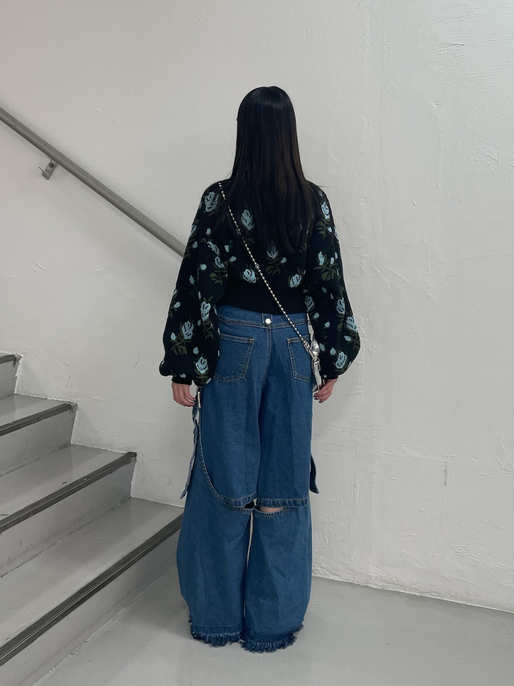ブルー系のデニムパンツ、ブラック系のカーディガン/ボレロ、シルバー系のハンドバッグを着用したレディースの秋コーディネートの5枚目の写真