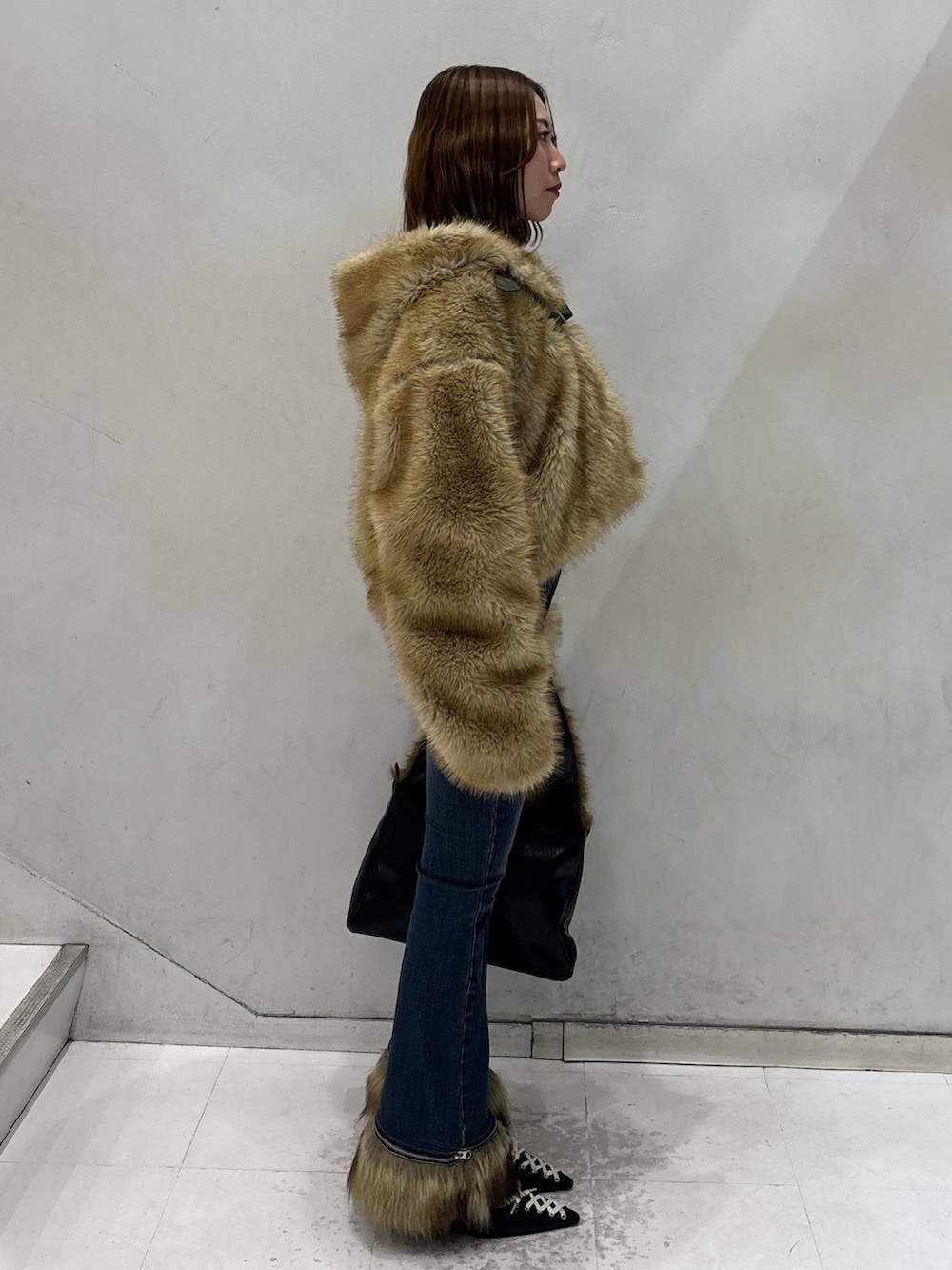 ブルー系のデニムパンツ、ブラック系のハンドバッグ、ブラック系のパンプスを着用したレディースの秋コーディネートの3枚目の写真