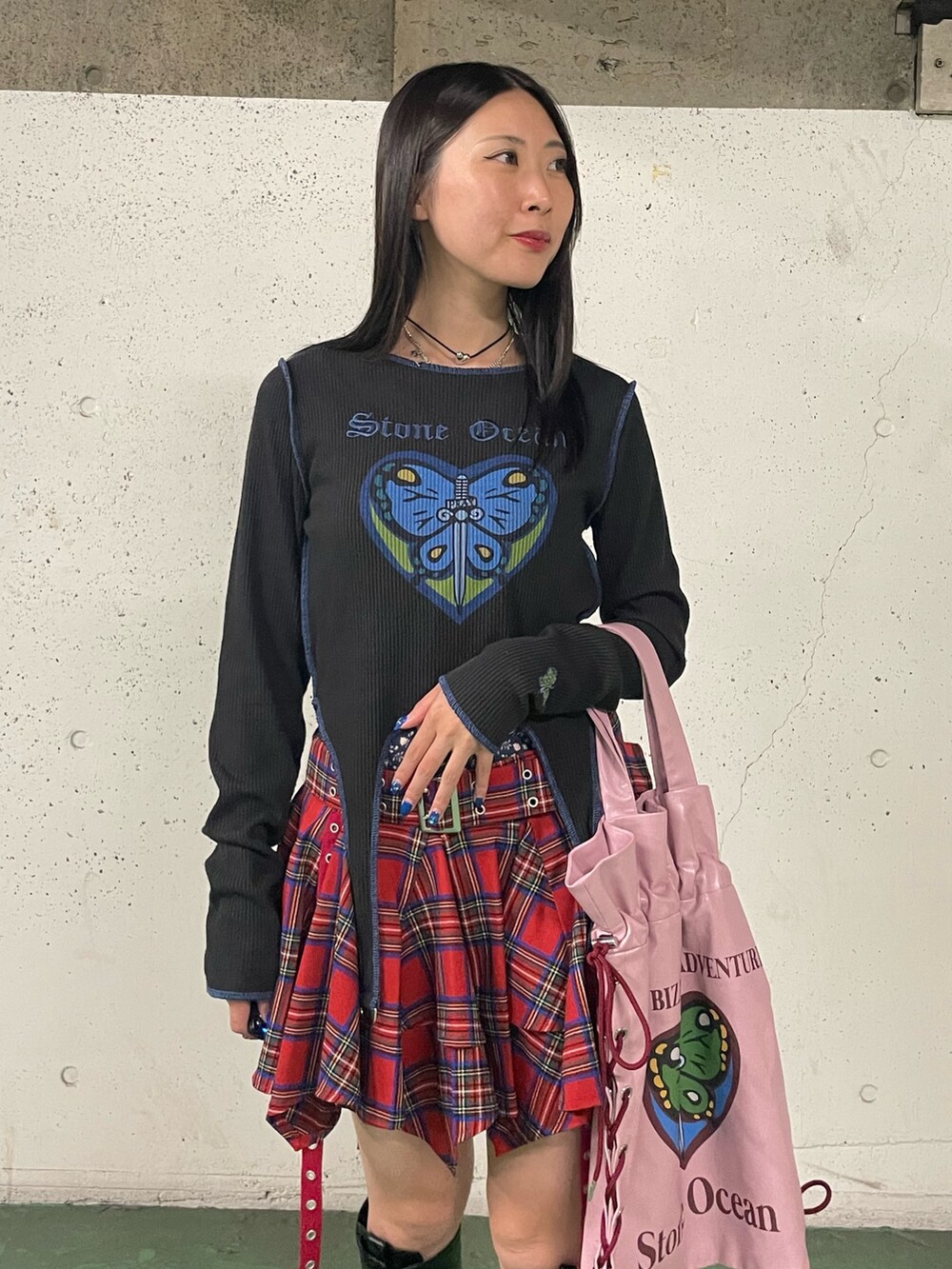 レッド系のスカート、ブラック系のブーツ、ブラック系のTシャツ/カットソーを着用したレディースの秋コーディネートの6枚目の写真