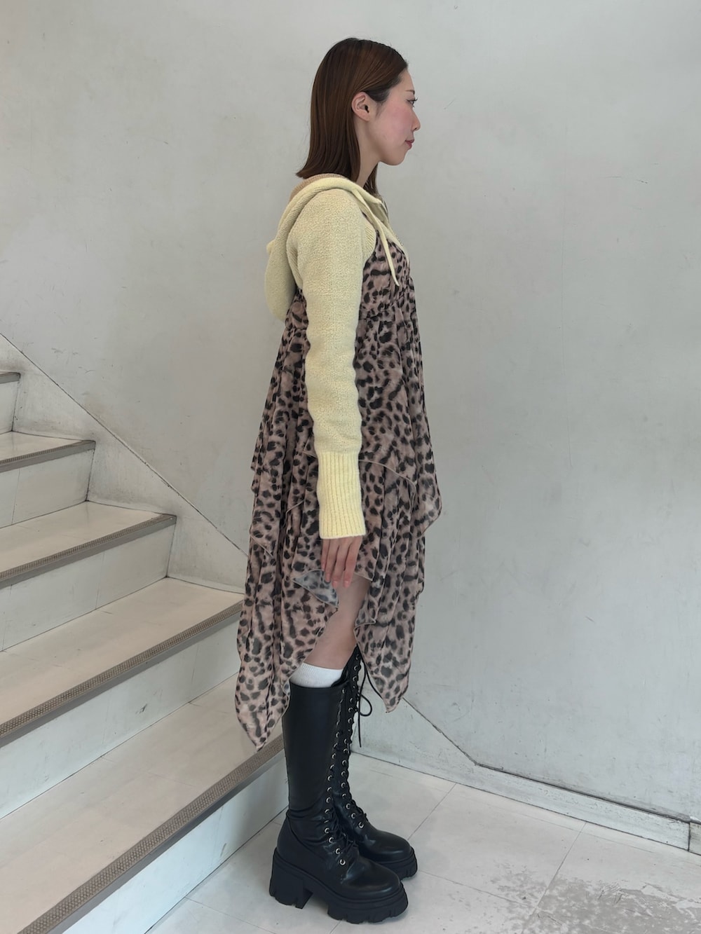 ブラウン系のワンピース、イエロー系のパーカー、ブラック系のブーツを着用したレディースの冬コーディネートの3枚目の写真