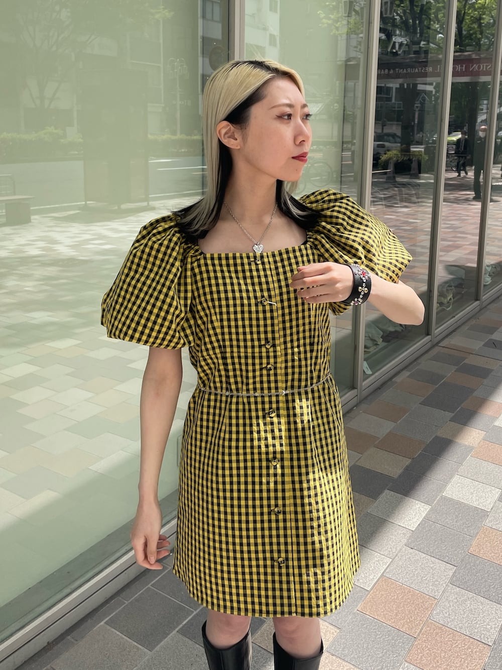 イエロー系のワンピース、ブラック系のブーツ、シルバー系のベルトを着用したレディースの春コーディネートの6枚目の写真