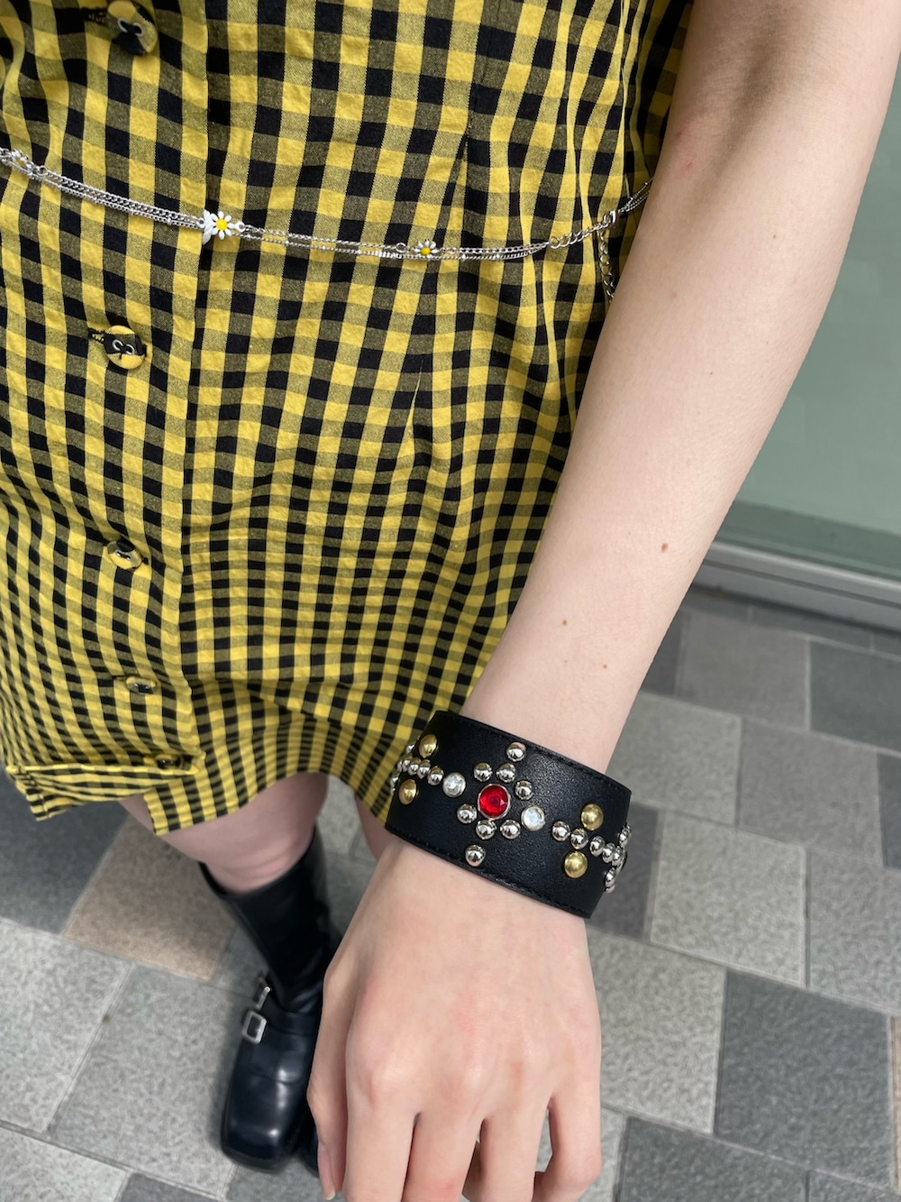 イエロー系のワンピース、ブラック系のブーツ、シルバー系のベルトを着用したレディースの春コーディネートの9枚目の写真